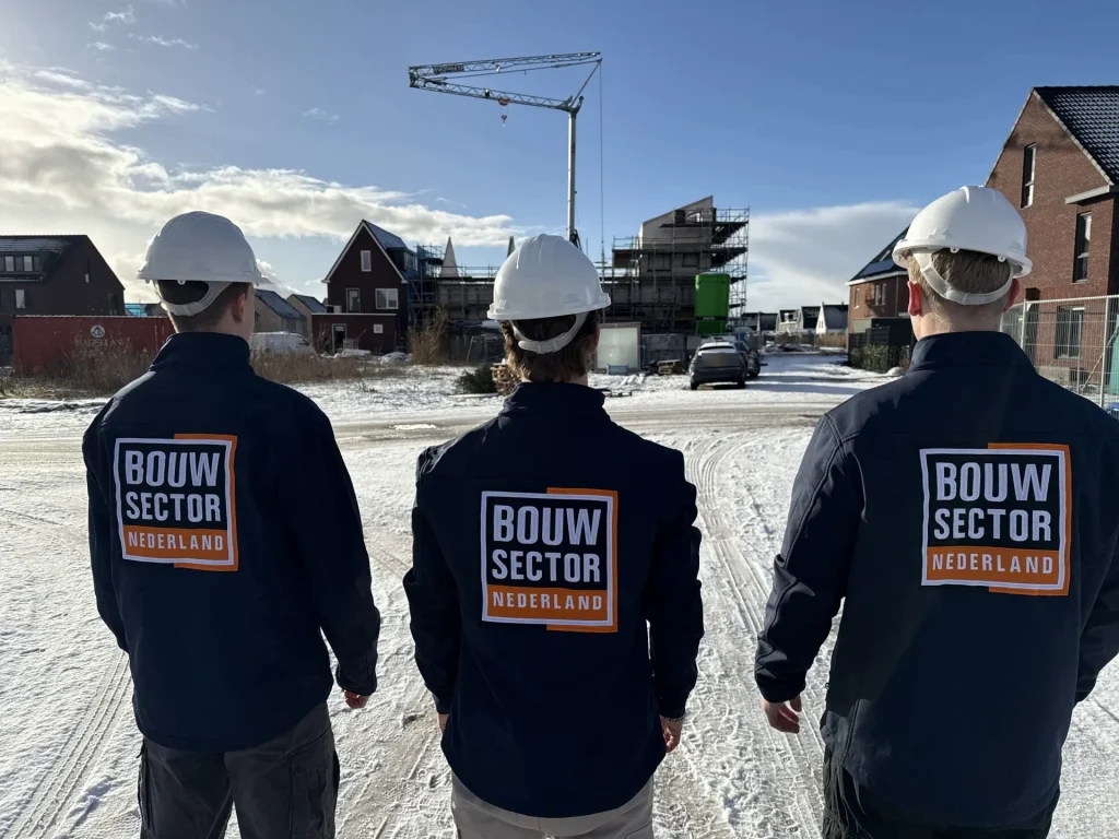 Drie vakmensen van Bouwsector Nederland met witte helm op een bouwstraat met nieuwe woningen