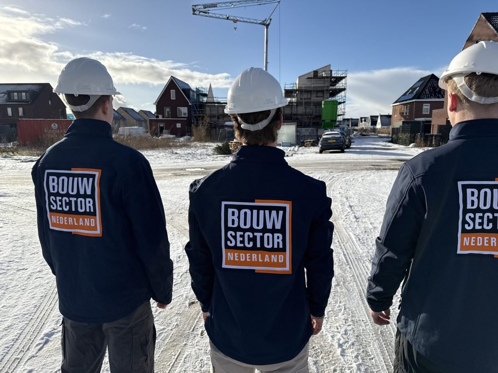 Vakmensen van Bouwsector Nederland met helm kijken naar gevels van woningen in aanbouw